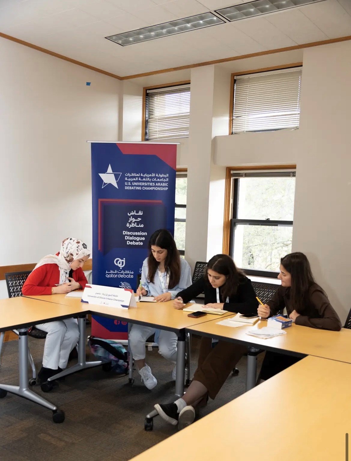 Four members of Arabic Debate Team sitting at table working on their debate