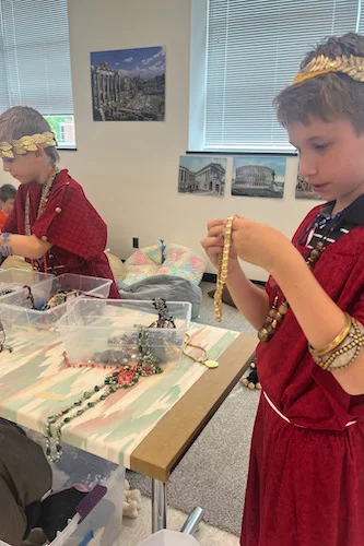 Two campers trying on Roman clothing and accessories 