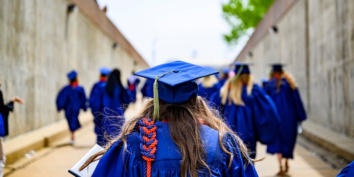 Graduate in regalia walking away from camera