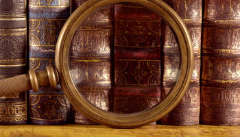 Ancient old books and magnifying glass 