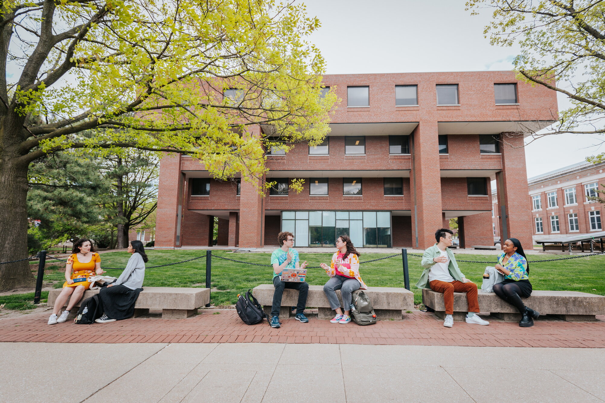 Students posing on benches outside Literatures, Cultures & Linguistics Building
