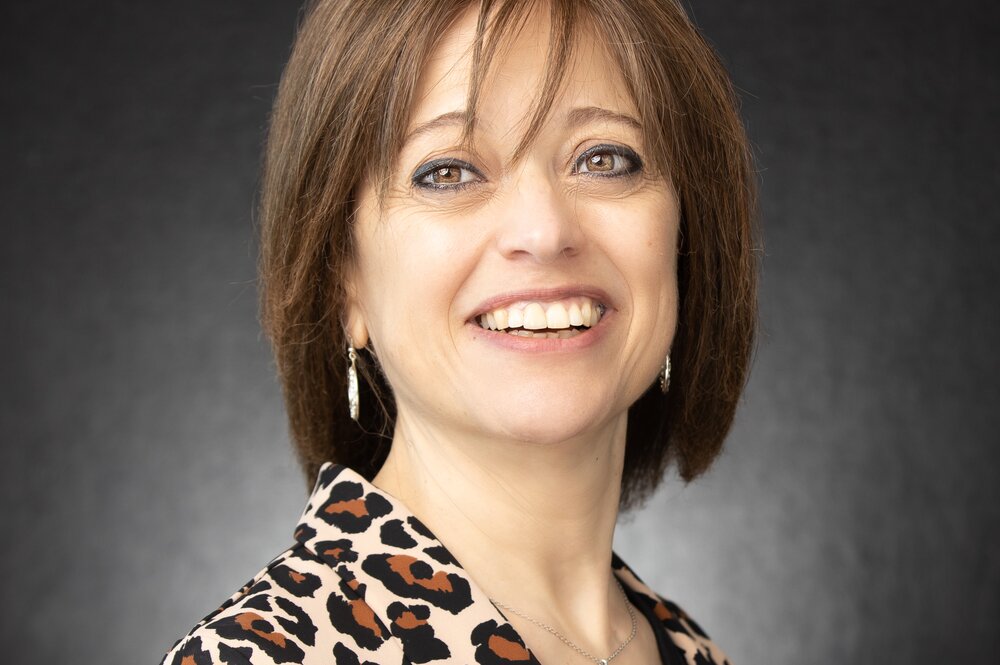Headshot of woman with short brown hair and leopard print shirt