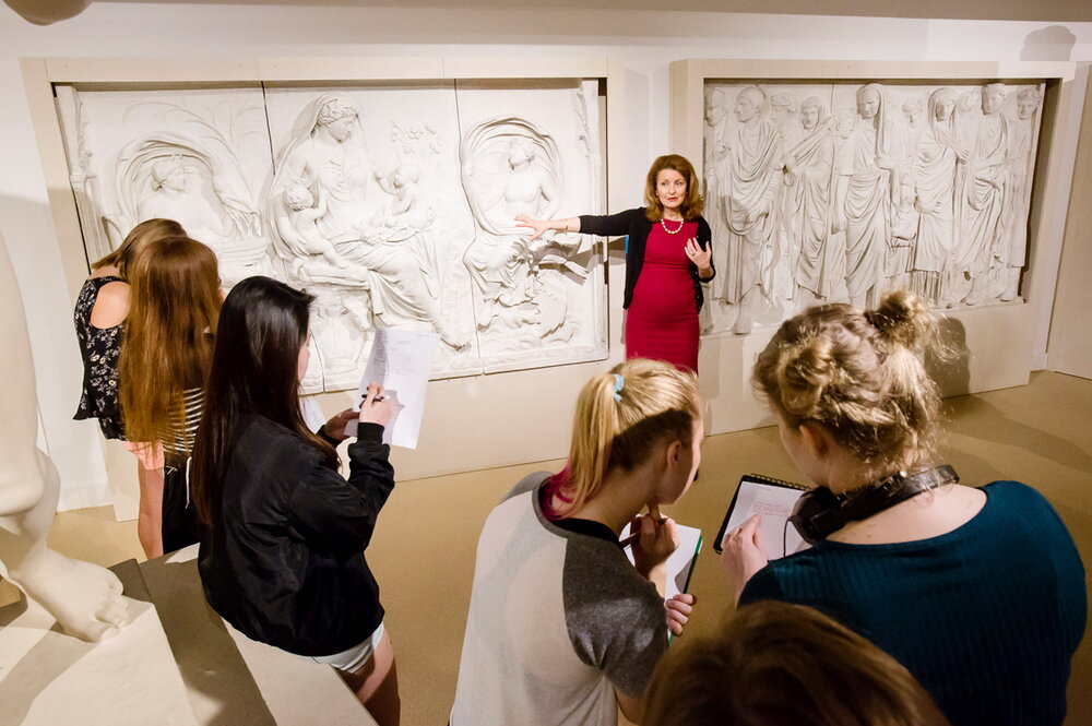 Classics professor in red dress giving lecture at Spurlock Museum