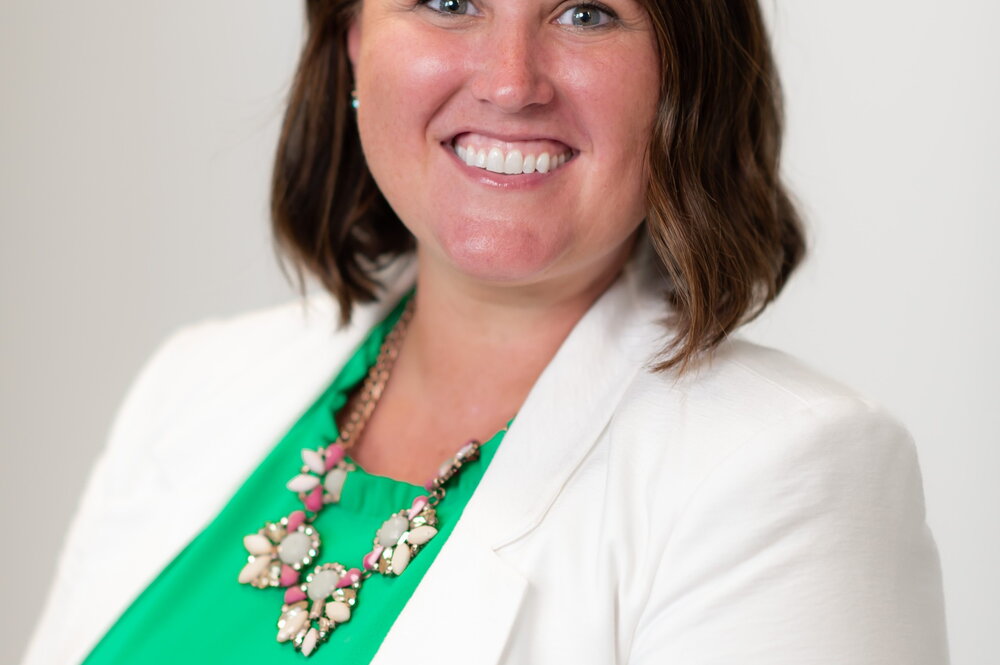 Smiling woman in green blouse and white blazer