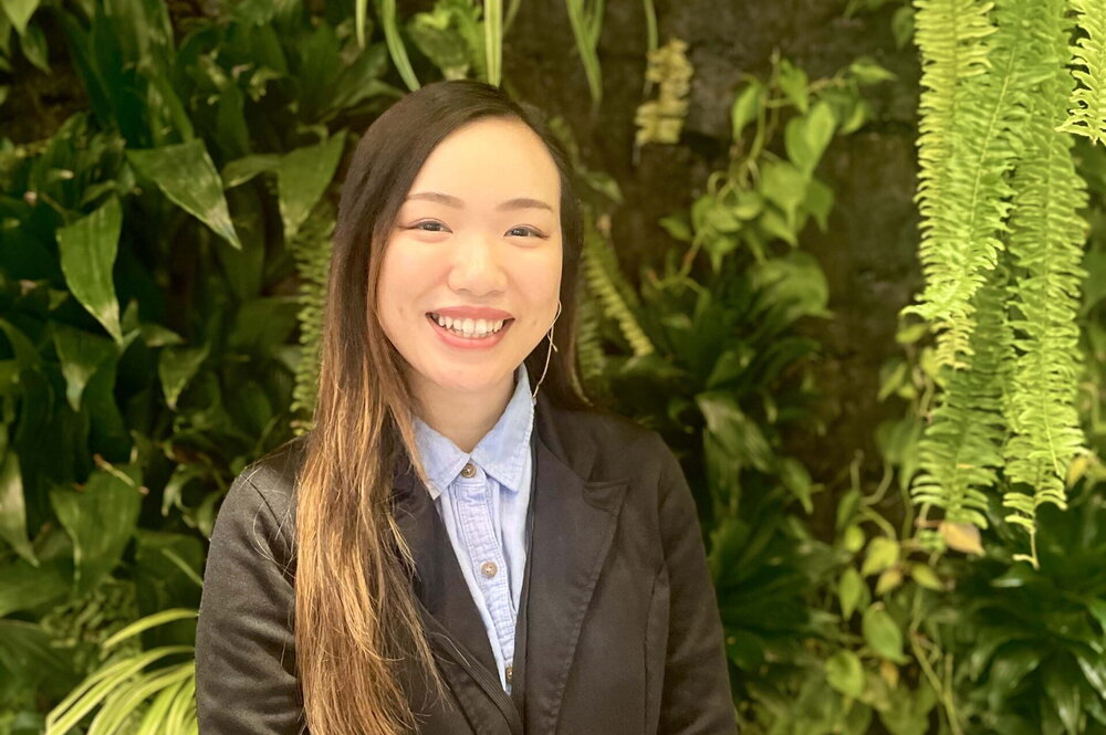 Young woman standing in front of greenery