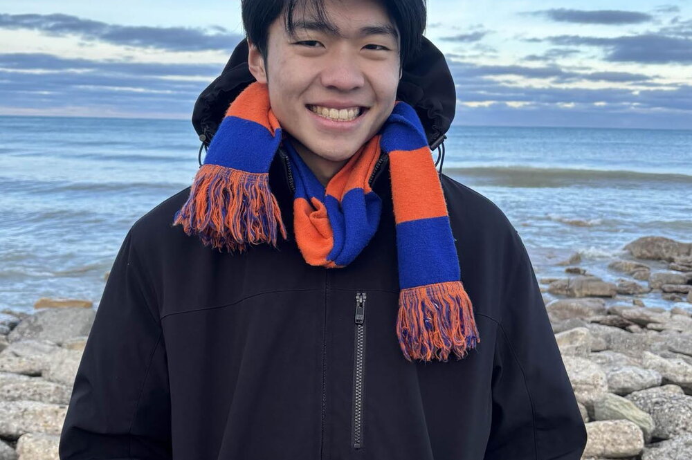 Smiling young man in black hoodie and orange and blue scarf