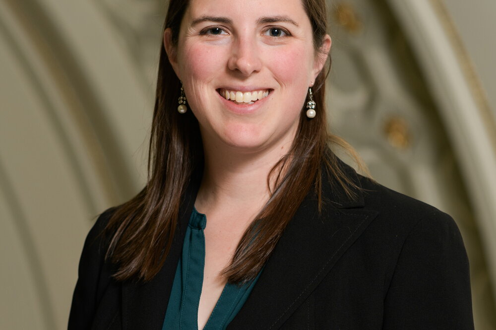 Headshot of woman in black blazer and dark shirt