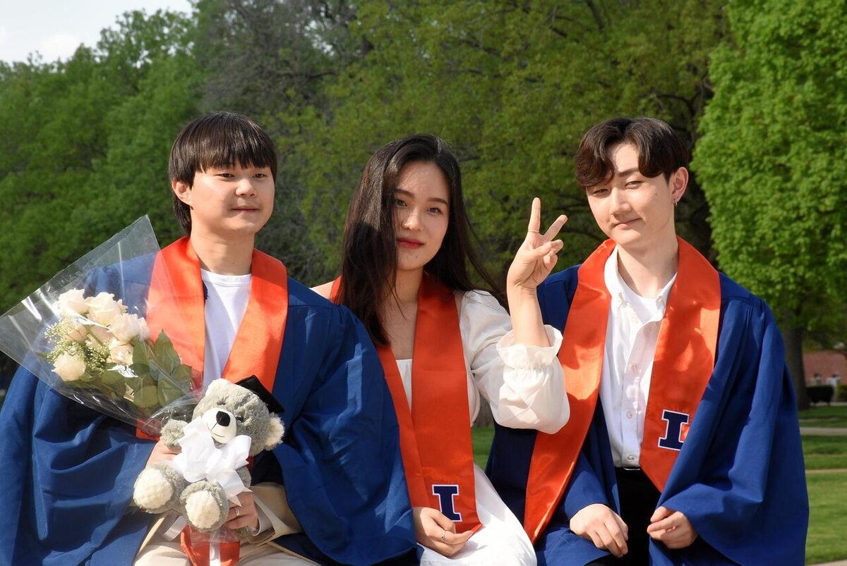 Three graduates smile and pose for picture