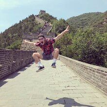Man in patterned shirt jumps for picture on brick bridge 