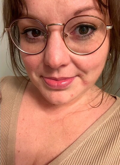 Selfie of brown-haired woman in round glasses