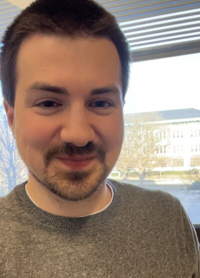 Smiling dark haired man in gray toned shirt