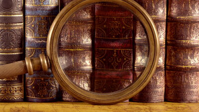 Still image of ancient old books and magnifying glass