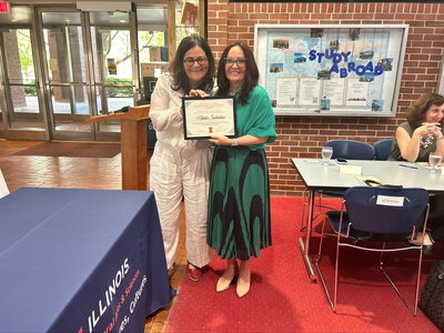 Two smiling women pose with award
