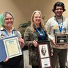 Two students and professor pose with awards