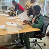 Young students sit at table and cut paper for a French activity