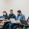 Four students sitting with laptops in a French classroom