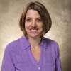 Headshot of short-haired woman in purple blouse