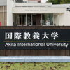 Student posing by university sign in Akita, Japan