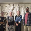 Four people stand in front of classical art display