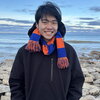 Smiling young man in black hoodie and orange and blue scarf
