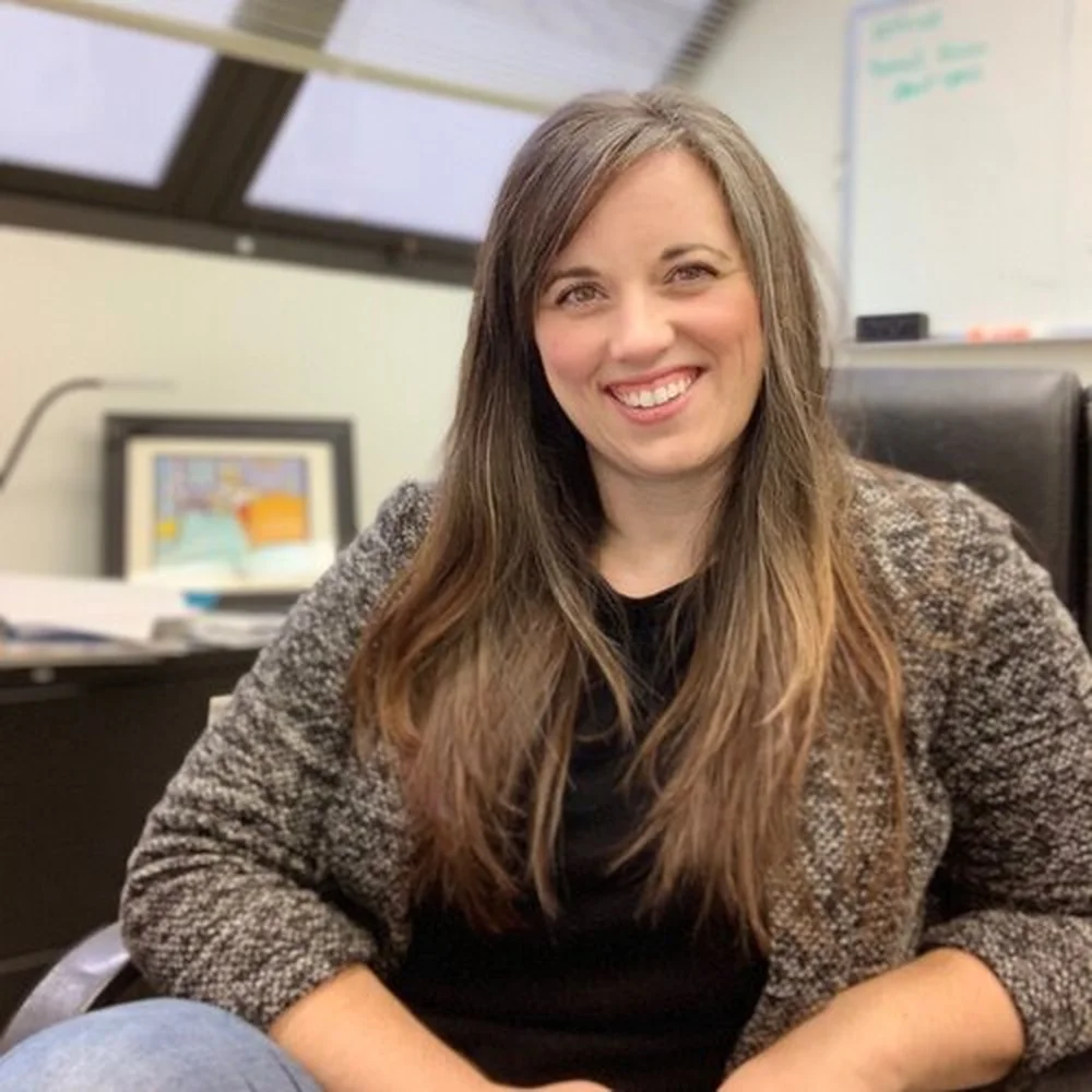 Smiling woman with long brown hair sitting in office chair