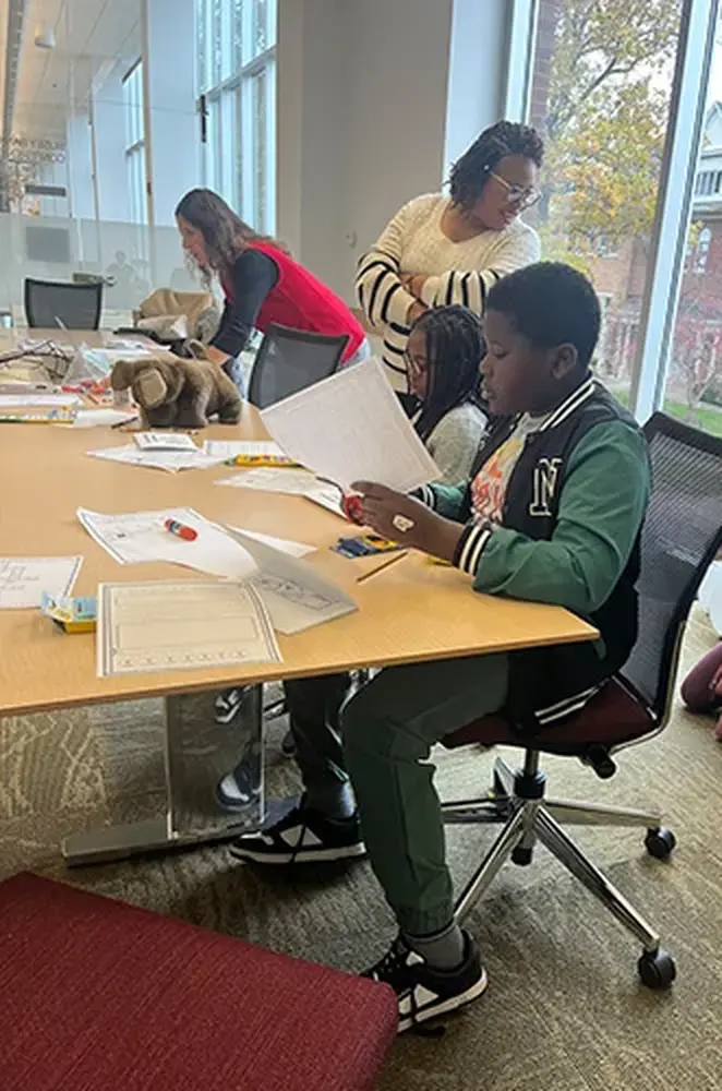 Young students sit at table and cut paper for a French activity