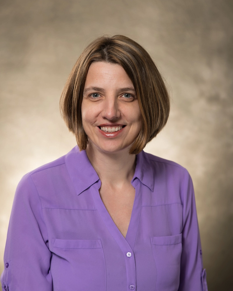Headshot of short-haired woman in purple blouse