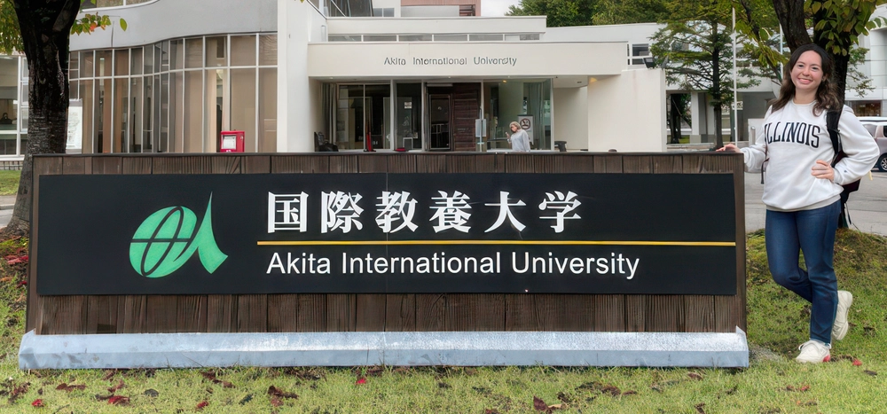 Student posing by university sign in Akita, Japan