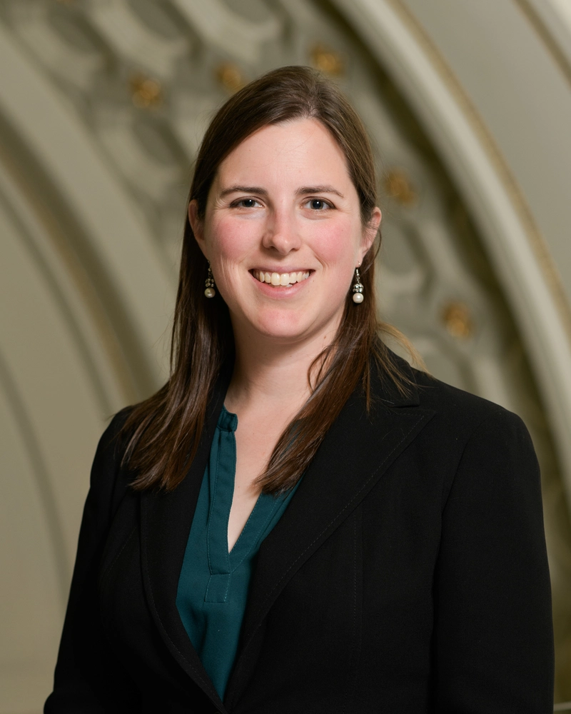 Headshot of woman in black blazer and dark shirt