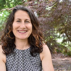 Woman in short-sleeve patterned shirt smiles 