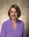 Headshot of short-haired woman in purple blouse