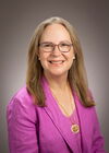 Headshot of smiling woman in pink blazer and top