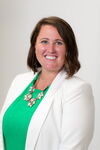 Smiling woman in green blouse and white blazer