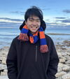 Smiling young man in black hoodie and orange and blue scarf