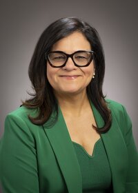 Smiling woman in glasses and a green shirt and blazer